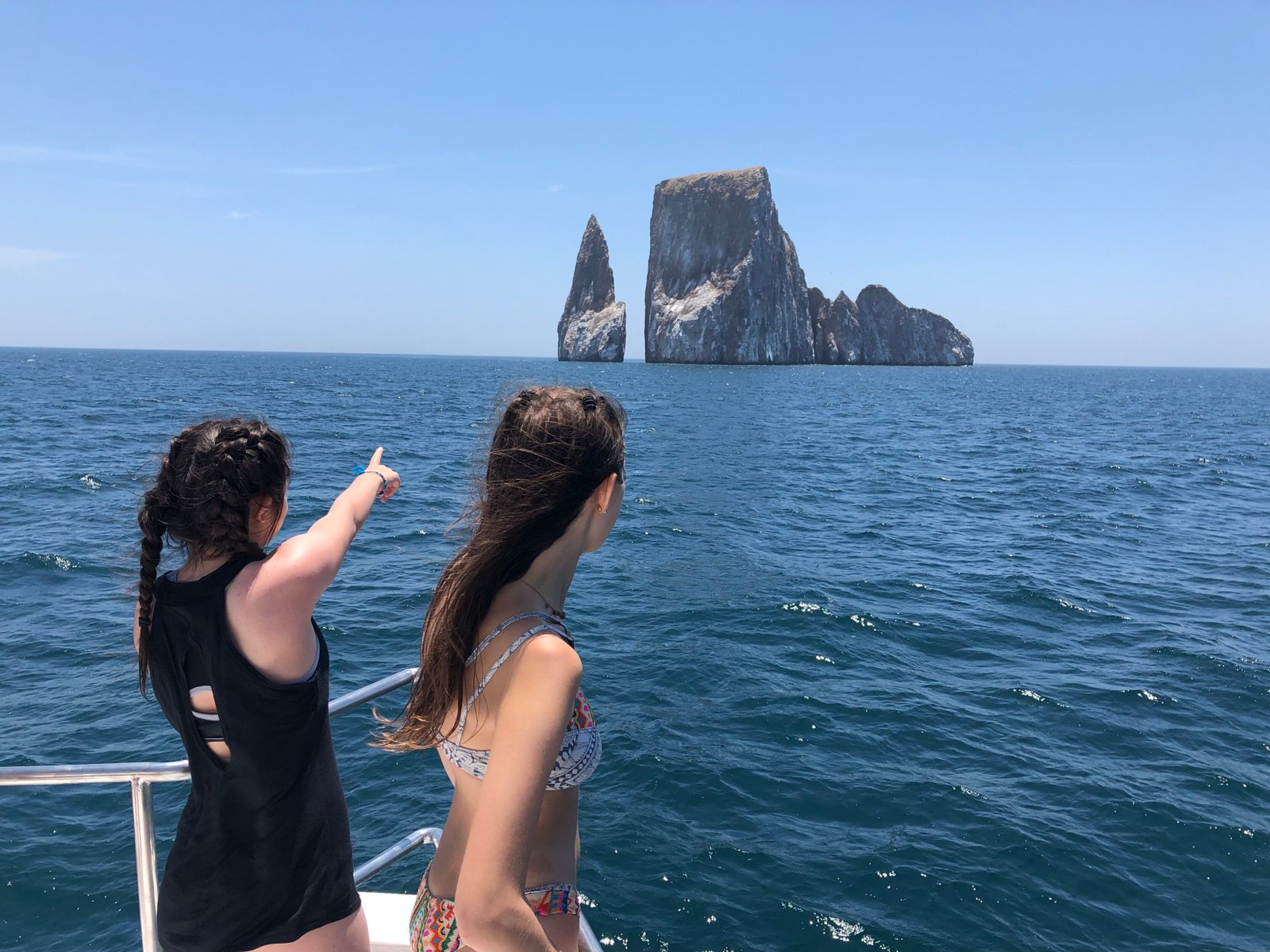 Two women pointing out into the horizon at an island, on an adventure of a lifetime, thanks to a travel designer at Finisterra Travel