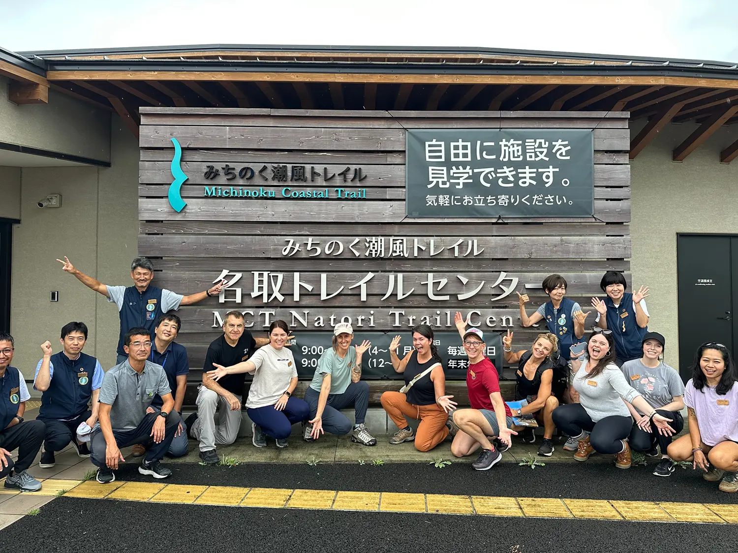 Group of local staff and international visitors smiling outside the MCT Natori Trail Center on the Michinoku Coastal Trail in Japan, symbolizing hospitality and community spirit